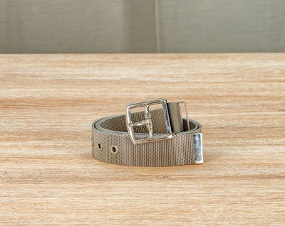 ceinture en métal argenté posée sur une surface en bois avec un fond gris