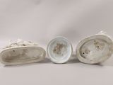 three porcelain figurines of a man and a woman on a white background