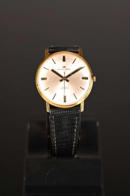 a close up of a watch on a stand on a black surface