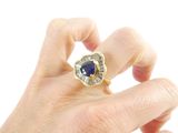 a person holding a ring with a blue stone in it
