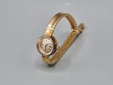 une montre en or posée sur une surface blanche