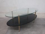 a glass coffee table with brass legs and a glass top