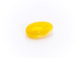 a close up of a yellow pill sitting on top of a white surface