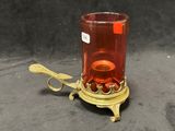 un bougeoir en verre rouge sur lequel est posée une cuillère
