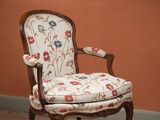 a chair with a floral upholstered seat in front of an orange wall