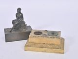 a small statue of a woman sitting on a box next to a small statue of a man