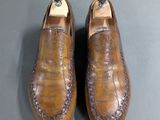 pair of men ' s brown leather shoes on a gray surface
