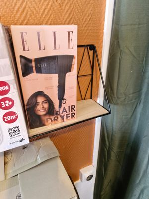 un sèche-cheveux posé sur une étagère à côté d'une boîte de sèche-cheveux