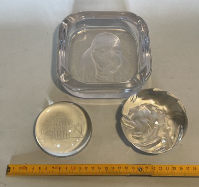 a glass ashtray and a silver ashtray on a table next to a ruler