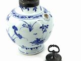 a blue and white vase with a black lid next to a small metal object