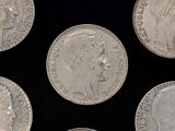 several silver coins with heads of people on them on a black surface