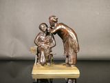 statue en bronze représentant une femme et un enfant assis sur un banc