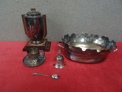 un bol en argent avec des cuillères et un repose-cuillères posé sur une table rouge