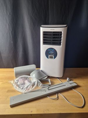 an air conditioner sitting on top of a wooden table next to a window