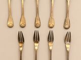 six forks are arranged in a row on a white surface