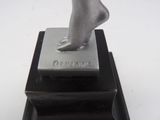 a silver statue of a woman standing on a black stand