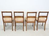 four wooden chairs are lined up against a white wall