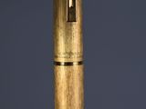 a close up of a wooden pen with a metal cap