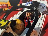 une photo d'un homme dans une voiture de course, portant un casque