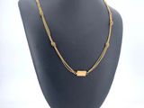 a black mannequin with a gold necklace on it