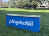 une boîte bleue avec un logo dessus, posée dans l'herbe