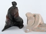 une statue représentant un homme assis sur une chaise, à côté d'une sculpture représentant un homme