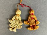two small ornaments are hanging from a string on a gray surface