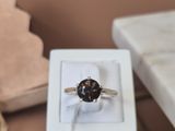 une bague en diamant noir dans une boîte blanche posée sur une table