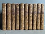 six old books are lined up on a table