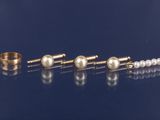 trois paires de boucles d'oreilles en perles et une bague en or posées sur un fond bleu
