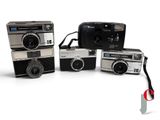 three old fashioned cameras sitting next to each other on a white surface