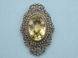 a close up of a broochle with a yellow stone in it