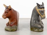 two figurines of a horse and a horse laying on the ground