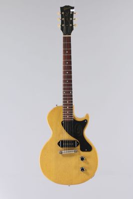 une guitare électrique jaune accrochée à un mur blanc