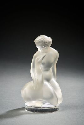 an image of a glass sculpture of a woman sitting on a rock