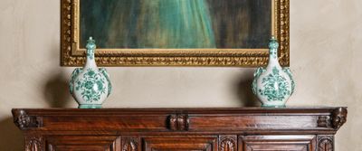deux vases posés sur le dessus d'un meuble, devant un tableau