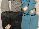 three pairs of jackets and pants sitting on top of a table