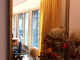 un miroir posé sur une table, devant lequel se trouve un vase de fleurs