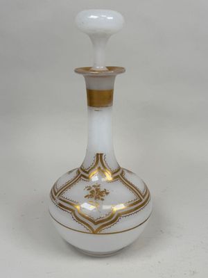 un vase blanc et doré posé sur une surface blanche