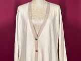 beige cardigan sweater on a mannequin stand against a red wall