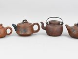 three small teapots and a teapot on a white surface