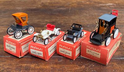 quatre petites voitures posées sur des cartons, sur une table en bois
