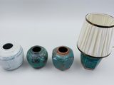 three vases and a lamp on a white surface