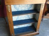 une bibliothèque en bois recouverte d'une moquette bleue, sur laquelle est posée une lampe