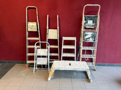 plusieurs échelles et une table dans une pièce dont l'un des murs est rouge