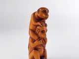 une vieille statue en bois représentant un singe portant un bébé sur le dos