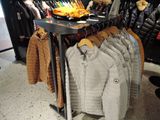 many coats and jackets hanging on a rack in a store