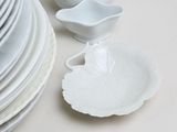 a stack of white plates and bowls on a table