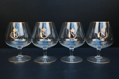 trois verres à vin vides, aux bords dorés, sont posés sur une table