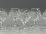 six crystal wine glasses are lined up on a white surface